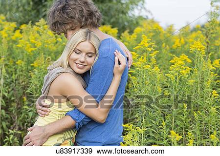 Side view of affectionate couple hugging in field View Large Photo Image Stock Photo - Side view of affectionate couple hugging in field. Fotosearch