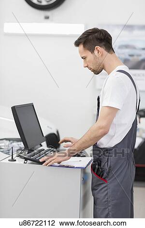 Side view of automobile mechanic using computer in workshop View Large Photo Image Stock Image - Side view of automobile mechanic using computer in workshop. Fotosearch