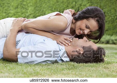 Side view of loving woman lying on man in park View Large Photo Image Stock Photograph - Side view of loving woman lying on man in park. Fotosearch