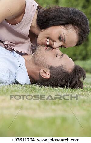 Side view of loving young couple about to kiss in park View Large Photo Image Picture - Side view of loving young couple about to kiss in park. Fotosearch