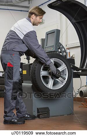 Side view of male mechanic repairing car's wheel in workshop View Large Photo Image Stock Photo - Side view of male mechanic repairing car's wheel in workshop. Fotosearch