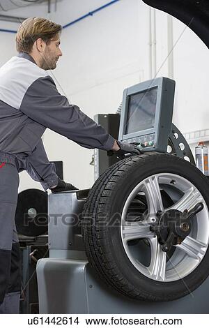 Side view of mid adult male mechanic repairing car's wheel in workshop View Large Photo Image Picture - Side view of mid adult male mechanic repairing car's wheel in workshop. Fotosearch