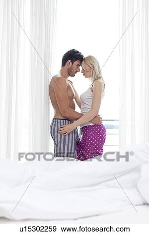 Side view of romantic young couple embracing in hotel room View Large Photo Image Stock Photo - Side view of romantic young couple embracing in hotel room. Fotosearch