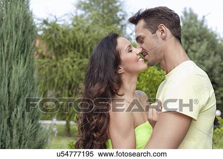 Side view of romantic young couple kissing in park View Large Photo Image Stock Photography - Side view of romantic young couple kissing in park. Fotosearch