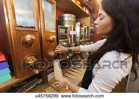 Side view of salesperson dispensing coffee beans into paper bag at store View Large Photo Image Stock Photo - Side view of salesperson dispensing coffee beans into paper bag at store. Fotosearch
