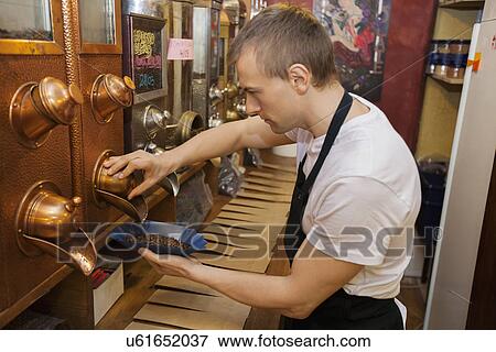 Stock Photo - Side view of salesperson dispensing coffee beans into bowl at store. Fotosearch