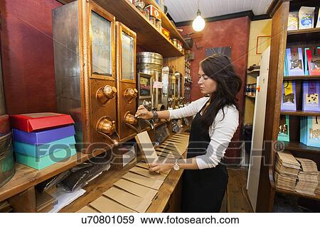 Stock Photo - Side view of salesperson dispensing coffee beans into paper bag at store. Fotosearch