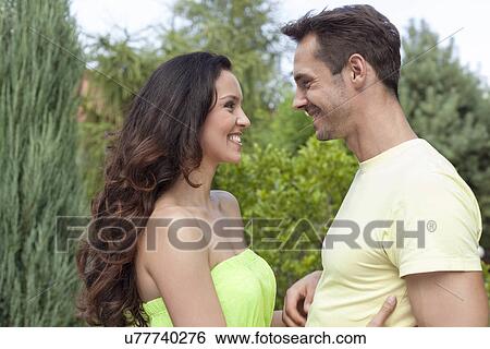 Side view of smiling young couple looking at each other in park View Large Photo Image Stock Photograph - Side view of smiling young couple looking at each other in park. Fotosearch
