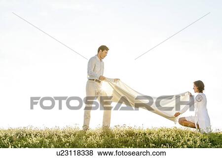 Side view of woman and man spreading picnic blanket on grass during sunny day View Large Photo Image Stock Photo - Side view of woman and man spreading picnic blanket on grass during sunny day. Fotosearch