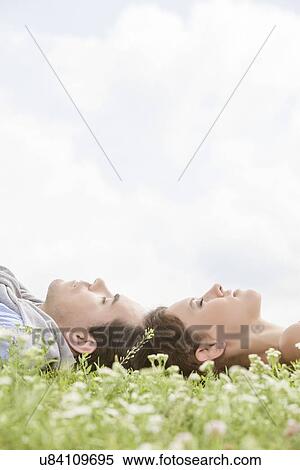 Side view of young couple sleeping on grass against sky View Large Photo Image Stock Photography - Side view of young couple sleeping on grass against sky. Fotosearch
