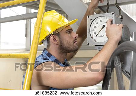 Side view of young male worker checking pressure gauge in industry View Large Photo Image Stock Image - Side view of young male worker checking pressure gauge in industry. Fotosearch