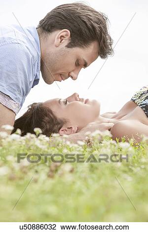 Side view of young man looking at woman sleeping on grass against sky View Large Photo Image Stock Image - Side view of young man looking at woman sleeping on grass against sky. Fotosearch