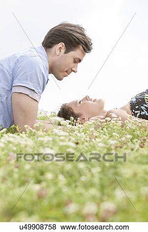 Side view of young man looking at woman sleeping on grass against sky View Large Photo Image Stock Photo - Side view of young man looking at woman sleeping on grass against sky. Fotosearch