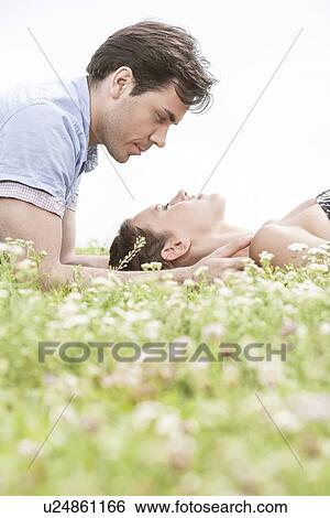 Side view of young man looking at woman sleeping on grass View Large Photo Image Stock Photograph - Side view of young man looking at woman sleeping on grass. Fotosearch