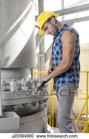 Side view of young manual worker using wrench on industrial machine View Large Photo Image Stock Image - Side view of young manual worker using wrench on industrial machine. Fotosearch