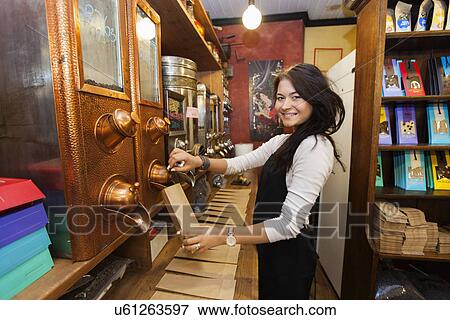 Side view portrait of female salesperson dispensing coffee beans into paper bag at store View Large Photo Image Stock Photo - Side view portrait of female salesperson dispensing coffee beans into paper bag at store. Fotosearch