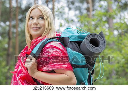 Side view smiling female backpacker in raincoat looking away at forest View Large Photo Image Stock Photo - Side view smiling female backpacker in raincoat looking away at forest. Fotosearch