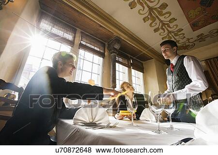 Stock Photo - Smiling business couple ordering food at restaurant table. Fotosearch