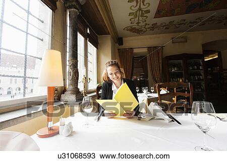 Smiling customer reading menu at restaurant table View Large Photo Image Stock Image - Smiling customer reading menu at restaurant table. Fotosearch