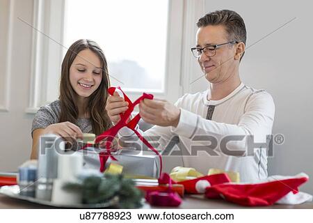 Smiling father and daughter wrapping Christmas present at home View Large Photo Image Stock Image - Smiling father and daughter wrapping Christmas present at home. Fotosearch