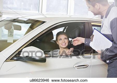 Smiling female customer receiving car key from mechanic in workshop View Large Photo Image Stock Photograph - Smiling female customer receiving car key from mechanic in workshop. Fotosearch