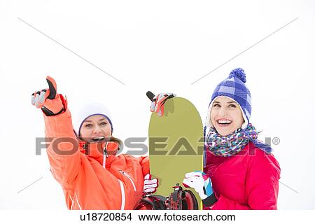 Smiling female friends with snowboard outdoors View Large Photo Image Picture - Smiling female friends with snowboard outdoors. Fotosearch