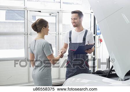 Smiling maintenance engineer shaking hands with female customer in car repair shop View Large Photo Image Stock Photography - Smiling maintenance engineer shaking hands with female customer in car repair shop. Fotosearch