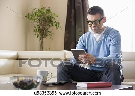 Stock Photography - Smiling man using tablet PC at home. Fotosearch