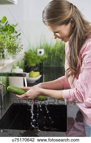 Smiling woman washing cucumber in kitchen View Large Photo Image Stock Image - Smiling woman washing cucumber in kitchen. Fotosearch