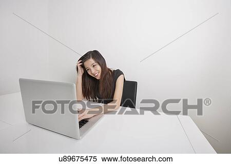 Smiling young businesswoman working on laptop at office desk View Large Photo Image Stock Photography - Smiling young businesswoman working on laptop at office desk. Fotosearch