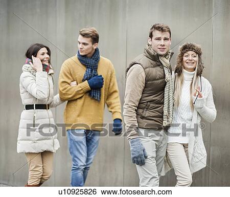 Smiling young couples walking against wall View Large Photo Image Stock Photograph - Smiling young couples walking against wall. Fotosearch