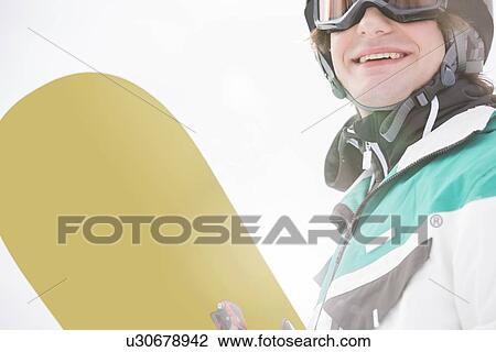 Smiling young man holding snowboard View Large Photo Image Stock Image - Smiling young man holding snowboard. Fotosearch