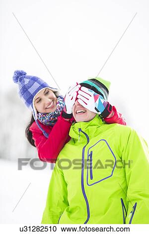 Smiling young woman covering man's eyes in winter View Large Photo Image Stock Image - Smiling young woman covering man's eyes in winter. Fotosearch