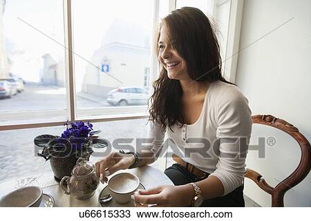 Smiling young woman having coffee at cafe View Large Photo Image Stock Image - Smiling young woman having coffee at cafe. Fotosearch