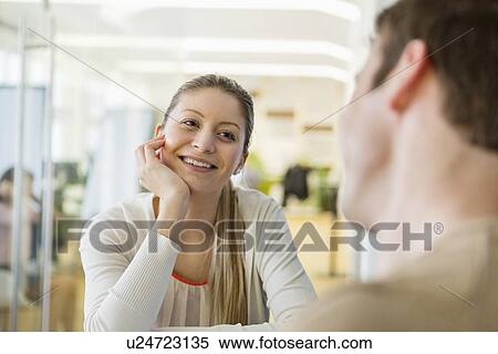 Smiling young woman looking at man in restaurant View Large Photo Image Stock Photography - Smiling young woman looking at man in restaurant. Fotosearch