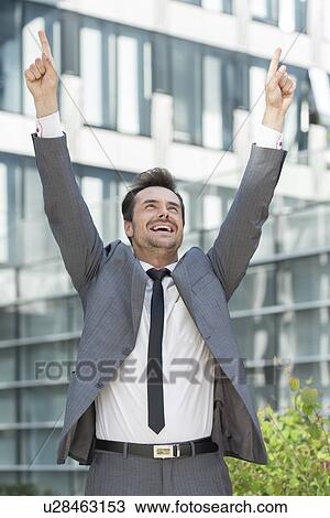 Successful businessman pointing upwards outside office building View Large Photo Image Stock Image - Successful businessman pointing upwards outside office building. Fotosearch