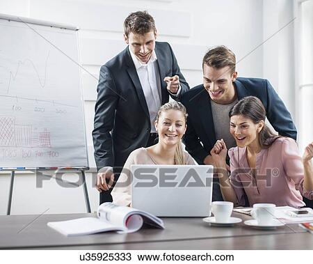 Stock Image - Successful young business people using laptop in meeting. Fotosearch