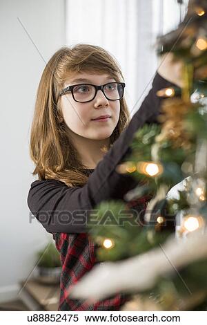 Teenage girl decorating Christmas tree at home View Large Photo Image Stock Photography - Teenage girl decorating Christmas tree at home. Fotosearch