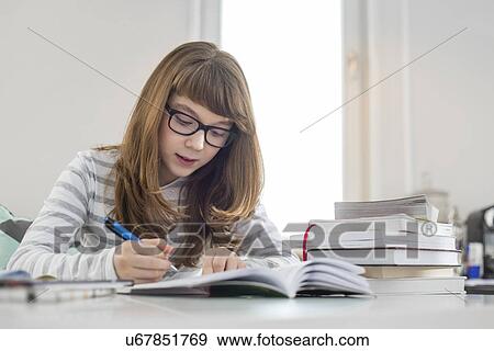 Teenage girl doing homework at table in house View Large Photo Image Stock Photo - Teenage girl doing homework at table in house. Fotosearch