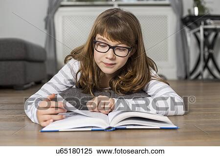 Teenage girl reading book while lying on floor at home View Large Photo Image Stock Photography - Teenage girl reading book while lying on floor at home. Fotosearch
