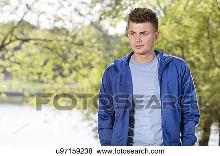 Stock Photo - Thoughtful fit young man standing in park. Fotosearch