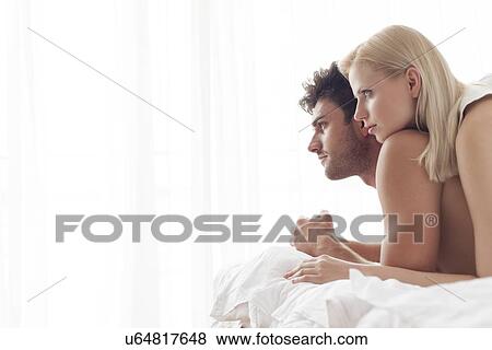 Stock Photo - Thoughtful young couple in bed. Fotosearch