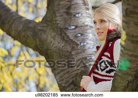 Thoughtful young woman in warm clothing standing near trees in park View Large Photo Image Stock Photography - Thoughtful young woman in warm clothing standing near trees in park. Fotosearch