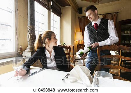 Waiter showing wine bottle to female customer at table in restaurant View Large Photo Image Stock Photo - Waiter showing wine bottle to female customer at table in restaurant. Fotosearch