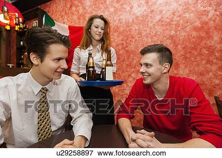 Waitress serving drinks to men in restaurant View Large Photo Image Stock Photo - Waitress serving drinks to men in restaurant. Fotosearch