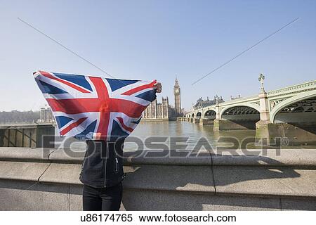 Stock Photography - Woman holding British flag in front of face against Big Ben at London, England, UK. Fotosearch