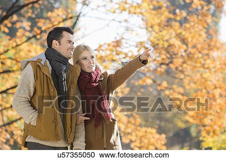 Woman pointing while standing with man in park during autumn View Large Photo Image Stock Image - Woman pointing while standing with man in park during autumn. Fotosearch