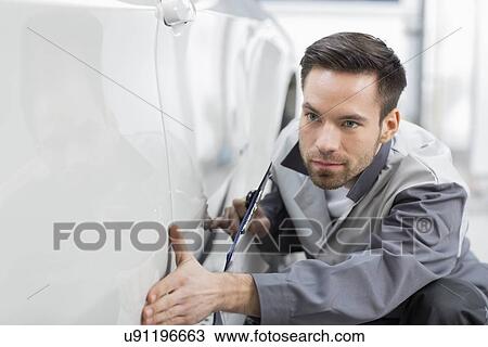 Young automobile mechanic examining car in repair store View Large Photo Image Stock Image - Young automobile mechanic examining car in repair store. Fotosearch