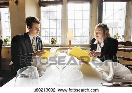Young business couple with menus at restaurant table View Large Photo Image Stock Image - Young business couple with menus at restaurant table. Fotosearch