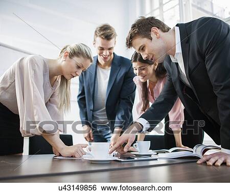 Stock Photograph - Young business people brainstorming at conference table. Fotosearch